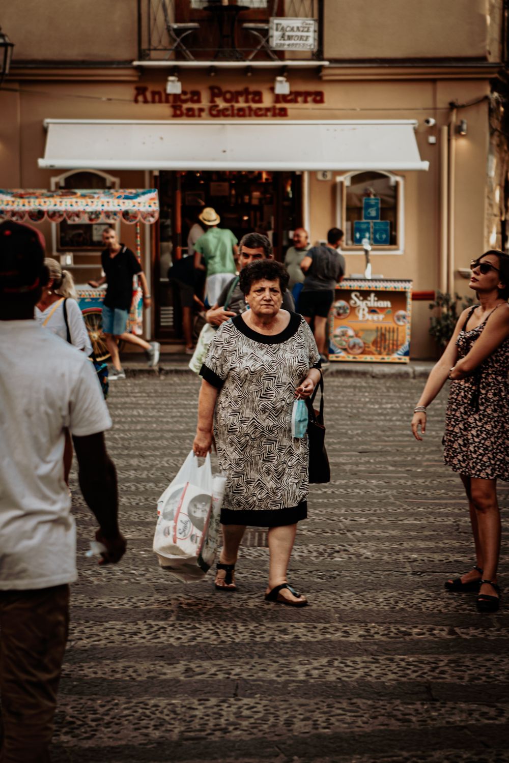 Pessoas em uma rua comercial, em uma cena de vida cotidiana.